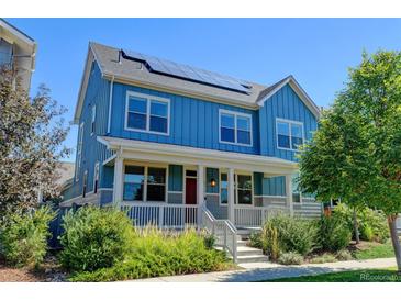 Inviting two-story blue home featuring a charming front porch and well-manicured landscaping at 5514 Uinta St, Denver, CO 80238