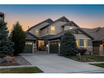 Charming two-story home featuring a well-manicured lawn, beautiful trees, and a three-car garage, all beneath a vibrant twilight sky at 10681 Sundial Rim Rd, Highlands Ranch, CO 80126