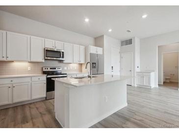 Bright kitchen featuring white cabinets, stainless steel appliances, and an island with quartz countertops at 487 Interlocken Blvd # 409, Broomfield, CO 80021