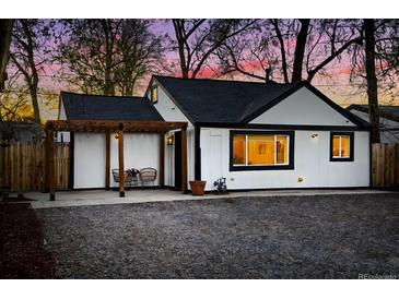Charming home exterior at twilight with black trim, pergola, and seating area for relaxing outdoors at 1755 Ingalls St, Lakewood, CO 80214