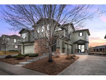 Inviting two-story home featuring a stone facade, mature landscaping, and a driveway leading to a two-car garage at 12941 Grant W Cir # C, Thornton, CO 80241