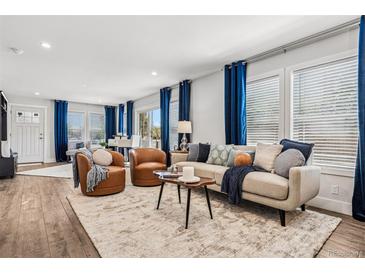 Bright living room with wood floors, tan sofa and blue curtains at 5202 Reed St, Arvada, CO 80002