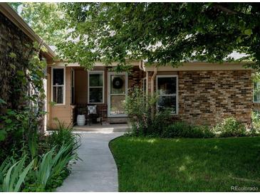 Charming brick home featuring a covered front porch, well-maintained landscaping, and a welcoming walkway at 12631 W Dakota Dr, Lakewood, CO 80228