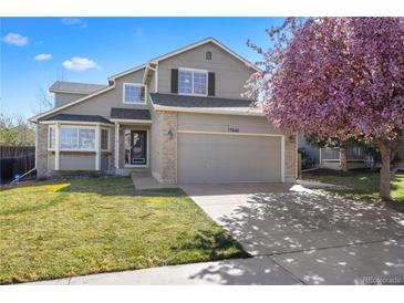 Charming two-story home featuring a well-manicured lawn and a beautiful flowering tree in the front yard at 13846 Harrison Dr, Thornton, CO 80602