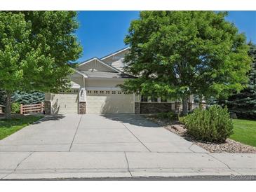 Charming two-story home with a three-car garage and a well-manicured front yard with mature trees at 5309 Mining Camp Trl, Parker, CO 80134