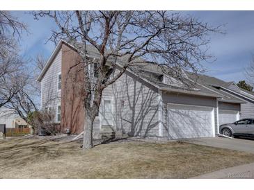 Charming townhouse featuring a two-car garage, gray siding, and a brick facade with a well-maintained front yard at 13901 E Oxford Pl, Aurora, CO 80014