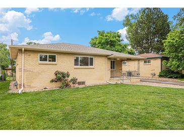 Charming brick home features a well-manicured lawn, flower bushes, and classic architectural details at 260 Flint Way, Broomfield, CO 80020