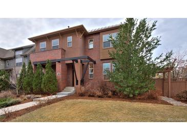 Charming two-story home with a brick and stucco facade and a well-manicured front yard with mature trees at 8044 E 24Th Ave, Denver, CO 80238
