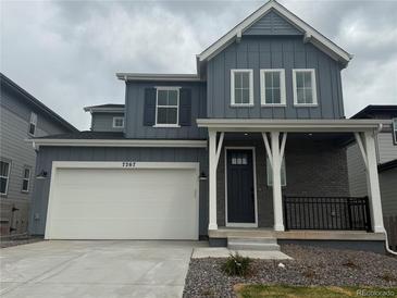 Charming two-story home with a blue exterior, a covered porch, and a two-car garage, set against a cloudy sky at 7267 Prairie Sage Pl, Littleton, CO 80125