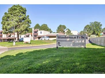 Exterior view of the Woodstream Falls community sign surrounded by lush greenery on a bright day at 9995 E Harvard Ave # 221, Denver, CO 80231