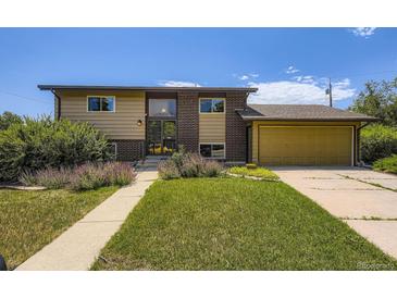 Two-story home with a brick and siding exterior, lush front lawn, and attached garage on a sunny day at 11462 W Tennessee Pl, Lakewood, CO 80226