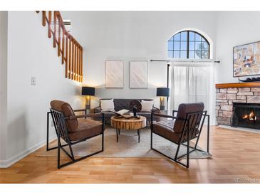 Inviting living room features a stone fireplace, two accent chairs, and stairway access to the second floor at 942 S Walden St # 204, Aurora, CO 80017