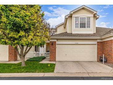 Inviting townhome with a two-car garage, brick details, and lush green lawn at 13545 W 62Nd Ln, Arvada, CO 80004
