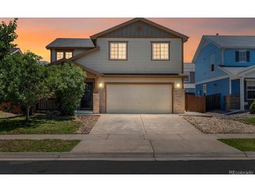 Charming two-story home with a two-car garage and well-maintained front yard at sunset at 5572 Kalispell St, Denver, CO 80239