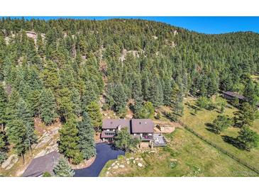 Secluded home nestled amongst mature trees with a large deck and convenient circular driveway at 31762 Horseshoe Dr, Evergreen, CO 80439