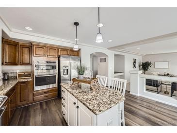 Bright kitchen featuring granite counters, island with seating, and stainless steel appliances at 5072 Cathay St, Denver, CO 80249