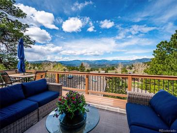 Inviting deck with wicker furniture offers breathtaking views of the mountains and picturesque scenery at 24172 Jerome Ct, Golden, CO 80401