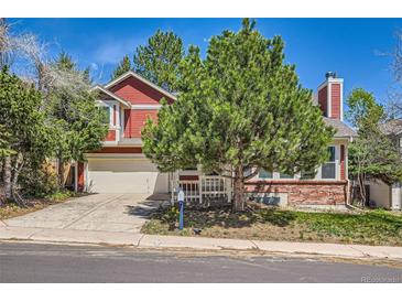 Charming two-story red home featuring brick accents, a well-manicured lawn, and a large tree at 17509 E Kenyon Dr, Aurora, CO 80013
