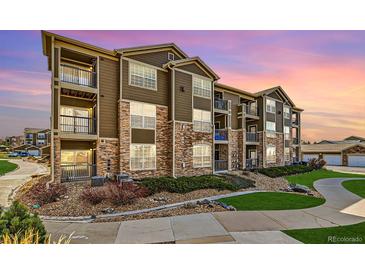 Beautiful condominium featuring a stone and siding exterior, balconies, and manicured landscaping at 2855 Blue Sky Cir # 3-102, Erie, CO 80516