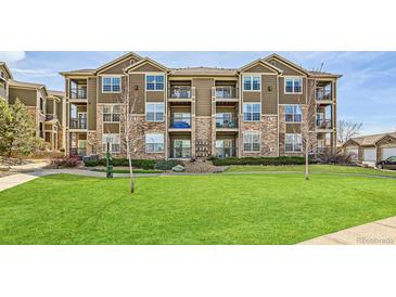 Attractive three-story condo building with stone accents and balconies overlooking a well-manicured lawn at 2855 Blue Sky Cir # 3-102, Erie, CO 80516