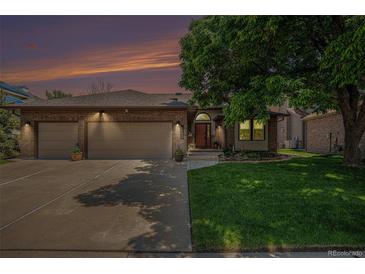 Charming brick home with a well-manicured lawn, mature tree, and attached three-car garage at 1152 Clubhouse Dr, Broomfield, CO 80020