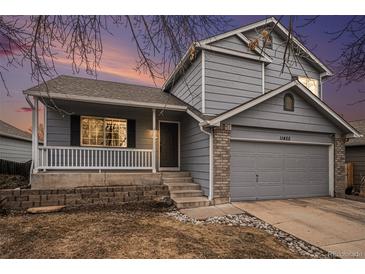 Two-story house with gray siding, brick accents, and a landscaped yard at 11455 River Run Pkwy, Commerce City, CO 80640