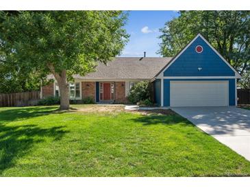 Ranch style home with blue siding, red door, and a well-manicured lawn at 3824 S Xenia St, Denver, CO 80237