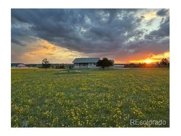 Beautiful home exterior at sunset with open field and cloudy sky, conveying peaceful rural living at 46531 Sundance Trl, Parker, CO 80138