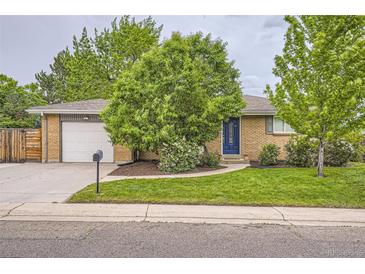 Charming brick home with a well-manicured lawn, a blue front door, and an attached garage at 6046 Vrain St, Arvada, CO 80003