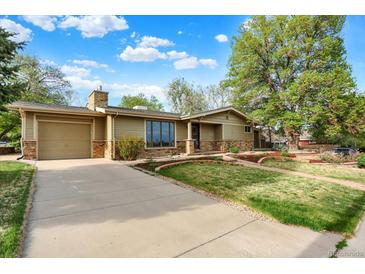 Charming single-story home with a well-manicured lawn, stone accents, and a spacious driveway at 7895 W 67Th Ave, Arvada, CO 80004