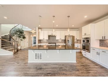 Well-lit kitchen features a central island with modern appliances and staircase at 1715 Pioneer Cir, Lafayette, CO 80026