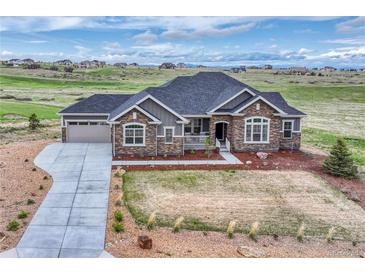 Beautiful single-story home with stone accents, a well-manicured lawn, and an attached two-car garage at 9727 Red Primrose St, Franktown, CO 80116