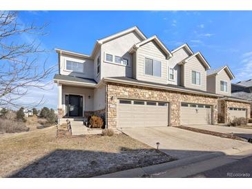 Charming townhouse with a two-car garage and stone accents on the exterior, offering a welcoming curb appeal at 5591 Canyon View Dr, Castle Rock, CO 80104