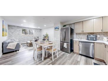 Open-concept living area with a dining table, stainless steel appliances, and a stylish stone accent wall at 8826 E Florida Ave # G12, Denver, CO 80247
