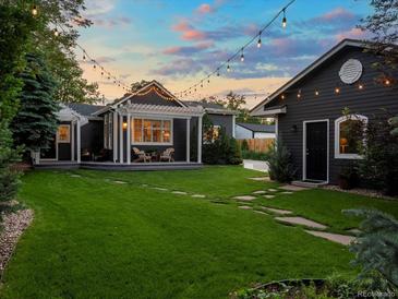 Charming backyard with green grass, stone pathway, pergola and string lights at dusk at 3339 Lowell Blvd, Denver, CO 80211