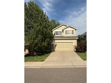 Charming two-story home with a well-maintained lawn, complemented by a mature tree and a spacious two car garage at 10386 Ravenswood Way, Highlands Ranch, CO 80130