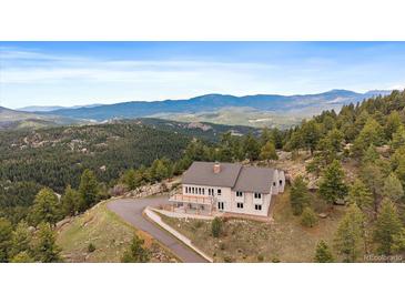 Stunning home boasts serene mountain views from a private, elevated location with a deck and a circular driveway at 5197 Bear Mountain Dr, Evergreen, CO 80439