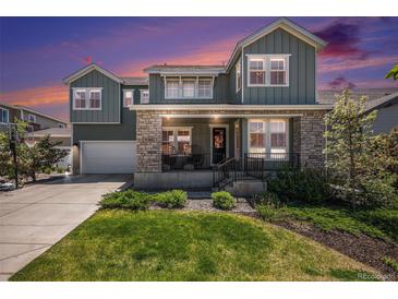 Inviting two-story home with a stone facade, manicured lawn, and a welcoming front porch at 9380 Bear River St, Littleton, CO 80125