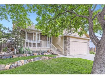 Charming two-story home with a stone facade, inviting front porch, and well-manicured lawn at 12021 Dahlia Dr, Thornton, CO 80241