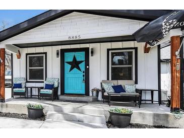 Charming home featuring a stylish front porch with cozy seating and a vibrant blue door at 8885 W 64Th Pl, Arvada, CO 80004