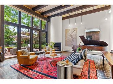 Bright living room featuring a fireplace, piano, large windows, and comfortable seating area at 50 Albion St, Denver, CO 80220