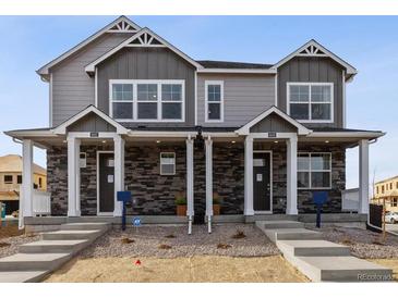 Charming townhome featuring stone accents, light gray siding and inviting covered front porches at 9865 Biscay St, Commerce City, CO 80022