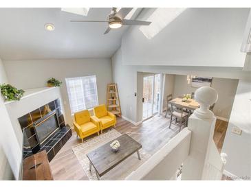 Inviting living room with vaulted ceilings, fireplace, and access to dining area, perfect for entertaining and relaxation at 3849 E 121St Ave, Thornton, CO 80241