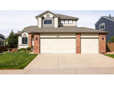 Inviting home exterior featuring a three-car garage and well-manicured lawn at 10218 Woodrose Ct, Highlands Ranch, CO 80129
