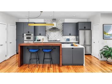 Modern kitchen features stainless steel appliances, stylish gray cabinetry, and a breakfast bar with seating at 1401 Delgany St # 203, Denver, CO 80202