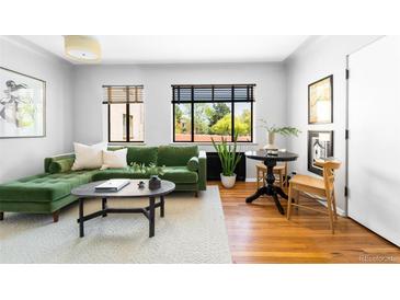 Bright living room featuring a comfortable green sofa, hardwood floors, and large windows with natural light at 1160 Birch St # 22, Denver, CO 80220