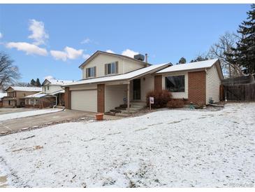 Two-story home with attached garage and brick facade, complemented by a snow-covered lawn on a sunny winter day at 10432 Canosa St, Denver, CO 80234