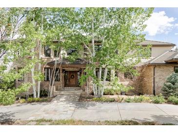 Charming brick home featuring a beautiful stone walkway, lush landscaping, and mature aspen trees at 5550 Preserve Dr, Greenwood Village, CO 80121