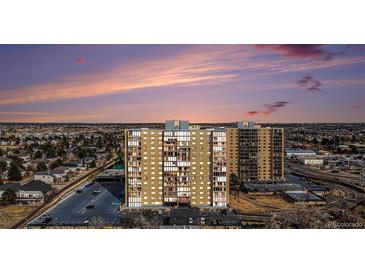 Stunning exterior view of a brick apartment building with a parking lot during sunset at 7865 E Mississippi Ave # 1102, Denver, CO 80247