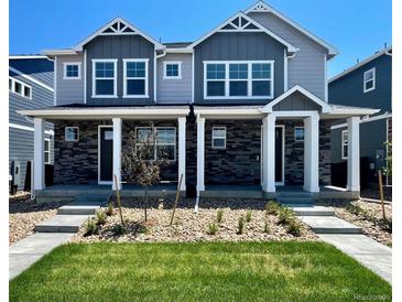 Modern two-story townhome with gray siding, stone accents, and a covered porch at 22375 E 6Th Ave, Aurora, CO 80018